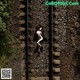 A naked woman laying on a train track.