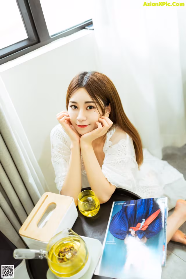 A woman sitting at a table with a book and a cup of tea.