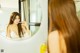 A woman brushing her teeth in front of a mirror.