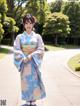 A woman in a blue kimono standing on a sidewalk.