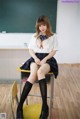 A woman sitting on a chair in front of a blackboard.