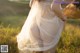 A woman in a white dress is walking through a field.