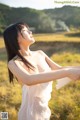 A woman in a white dress standing in a field.