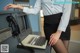 A woman in a skirt and shirt is sitting at a desk with a computer.