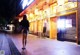 A woman walking down a sidewalk in front of a restaurant.