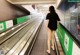 A woman walking down an escalator in a subway station.