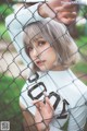 A woman in a white shirt leaning against a fence.