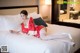 A woman in a red kimono laying on a bed.