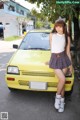 A woman standing in front of a yellow car.