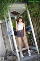 A woman standing in front of a pay phone booth.