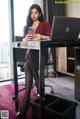 A woman sitting at a desk with a laptop and a cell phone.