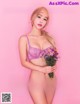 A woman in a purple lingerie holding a bunch of flowers.