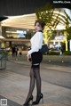 A woman in a white shirt and black skirt posing for a picture.