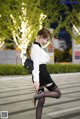 A woman in a white shirt and black skirt is walking down the street.