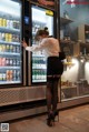 A woman standing in front of a refrigerator filled with drinks.