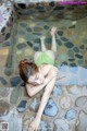 A woman in a green bikini laying in a pool of water.