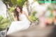 A woman in a wedding dress sitting on a wooden bench.