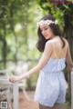 A woman in a blue dress with a flower crown on her head.