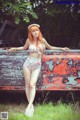 A woman in a bikini standing next to an old truck.