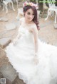 A woman in a wedding dress sitting on a rock.