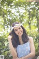 A woman in a blue dress with a flower crown on her head.