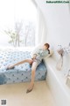 a woman sitting on top of a blue couch next to a window