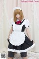 A woman dressed in a maid outfit posing for a picture.