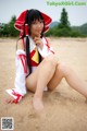 A woman in a red and white outfit sitting on a beach.