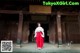 A woman in a red and white kimono standing in front of a building.