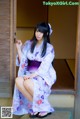 A woman in a kimono sitting on the steps of a building.