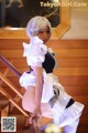 A woman in a maid outfit is posing on the stairs.