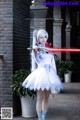 A woman in a white dress holding a red light saber.