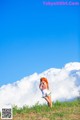 A woman in a sailor outfit standing on a grassy hill.