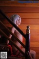 A naked woman sitting on the stairs of a house.