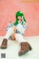 A woman with green hair sitting on a white surface.