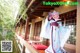 A woman in a blue and purple kimono standing on a porch.