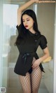 a woman in a black shirt and fishnet stockings posing for the camera