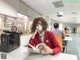 A woman wearing a face mask sitting at a table reading a book.