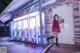 A woman wearing a face mask standing in front of a vending machine.